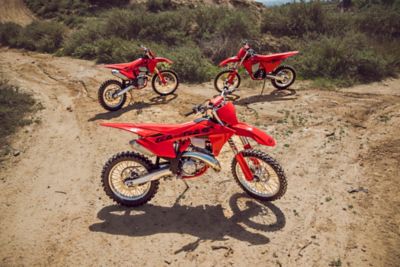 Tres motos de cross-country rojas están en el terreno.